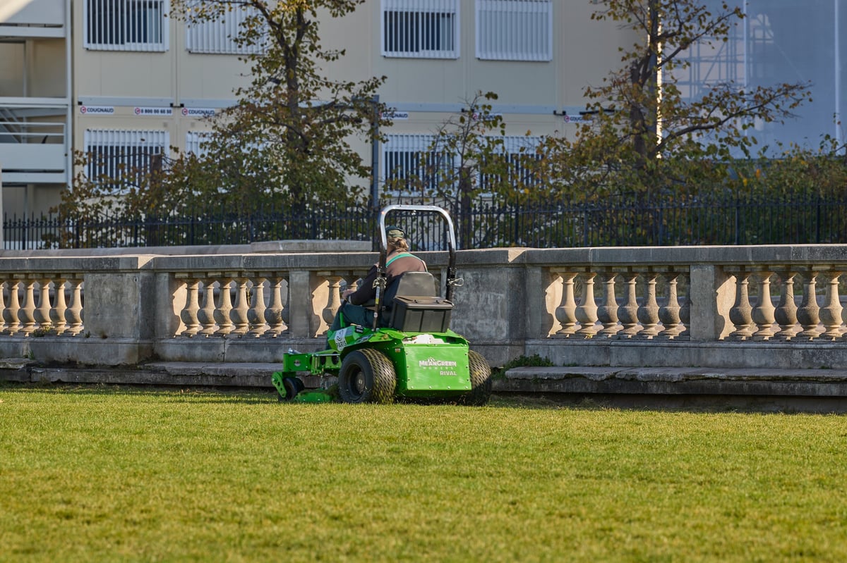 Gardener mowing lawn with professional equipment